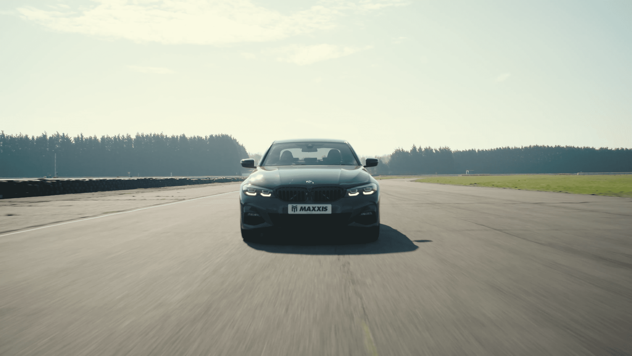 BMW on racetrack with MAXXIS name and logo on numberplate