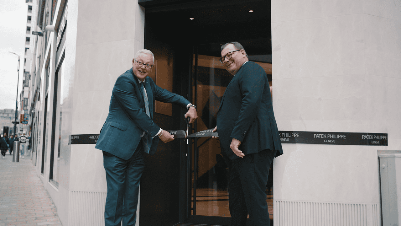 Two Men Cutting a Ribbon Outside a Patek Philippe Store